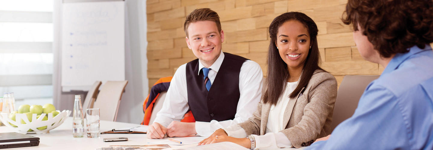 Strategie 2025 Drei Personen sitzen in einem hellen Raum an einem Tisch und sprechen gut gelaunt miteinander – eine typische Bewerbungs- oder Beratungssituation. Die Szene vermittelt Professionalität, Willkommenskultur und moderne HR-Arbeitswelt.