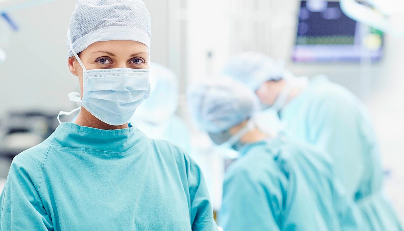Medizinische Versorgung Flughafen München – Schnell & Kompetent Ärztin im OP mit Team im Hintergrund – sichere medizinische Versorgung am Flughafen München.