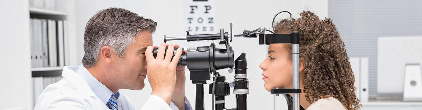 Augenärztliche Untersuchung am Flughafen München Ein Augenarzt untersucht das Auge einer Patientin mit einem Spaltlampen-Gerät in der Augenklinik am Flughafen München; beide sind im Profil zu sehen, die Atmosphäre wirkt konzentriert, ruhig und professionell.