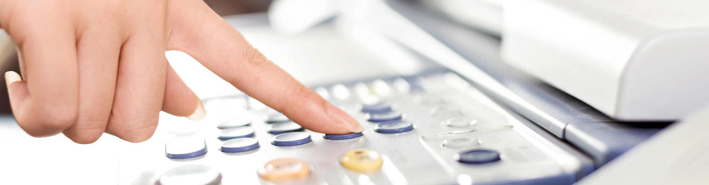 Kopieren und Drucken – Bedienung eines Multifunktionsgeräts Hand drückt eine Taste auf dem Bedienfeld eines Kopiergeräts.