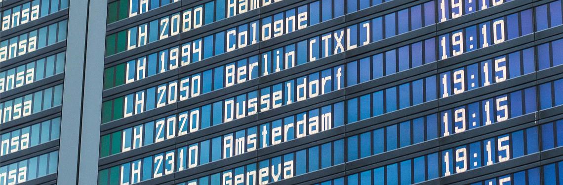 Flugplan-Anzeige am Flughafen München Nahaufnahme einer blauen digitalen Fluganzeigetafel am Flughafen München mit Flugnummern, Reisezielen wie Berlin und Amsterdam sowie Abflugzeiten; die Darstellung wirkt klar, strukturiert und gut lesbar.