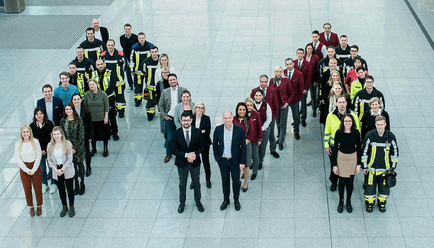 Auch als Arbeitgeber eine herausragende Marke Ein Markenzeichen mit Anziehungskraft – Mitarbeiter der Flughafen München GmbH (FMG) formierten sich zusammen mit dem Vorsitzenden der FMG-Geschäftsführung Jost Lammers (Mitte rechts) und Personalchef Dr. Robert Scharpf (Mitte links) zum bekannten Logo des Airports. In einem neuen bundesweiten Vergleich der besten Arbeitgeber belegt die FMG einen hervorragenden dritten Platz