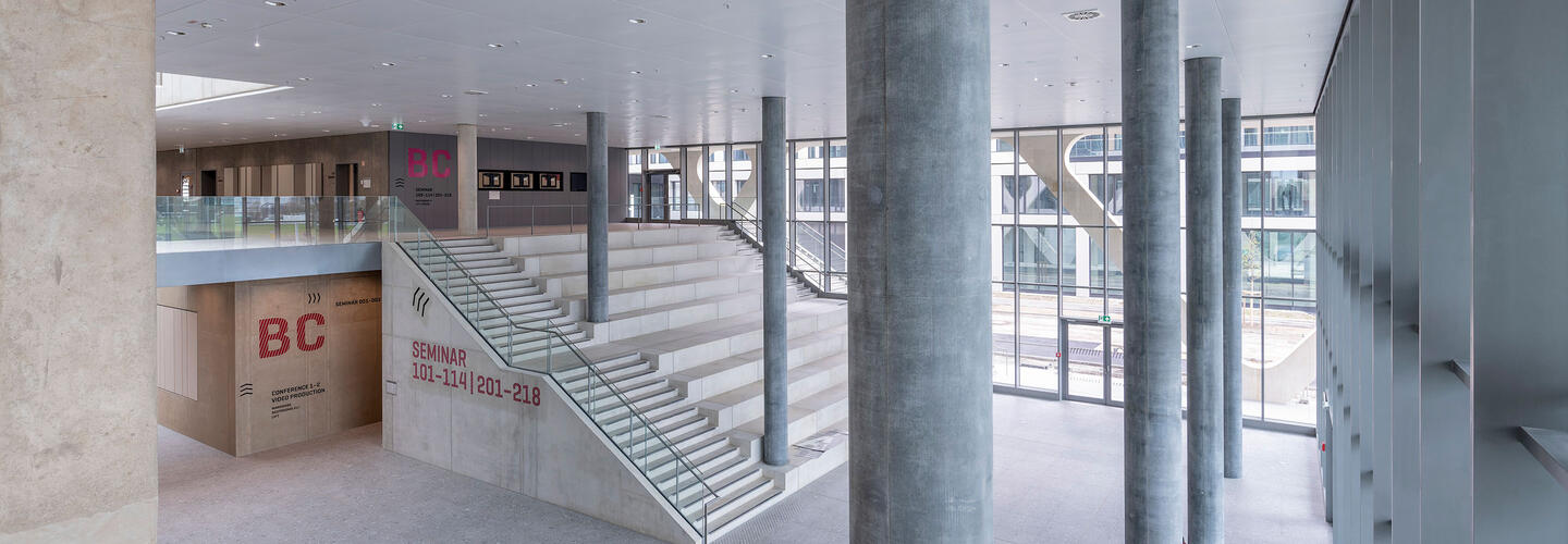 AirportAcademy - LAB 52 View of the light-flooded entrance hall with columns and a large staircase to sit down