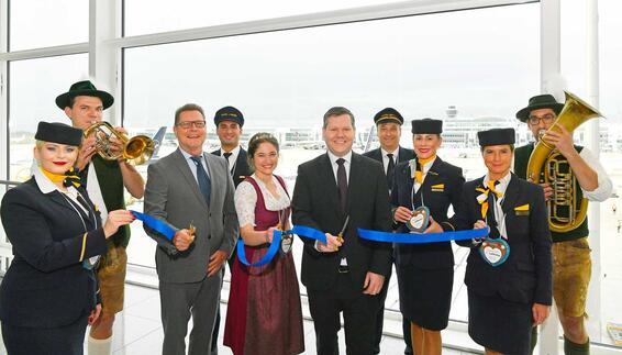 Vor dem Abflug wurde die neue Verbindung mit dem Durchschneiden eines Bandes gefeiert: Eingerahmt von einer Blaskapelle und der Crew der Lufthansa sind (in der Mitte von links) Thomas Kube, Vice President Route and Passenger Development des Münchner Flughafens, Simona Sommer, Bayerische Bierkönigin 2023 sowie Heiko Reitz, CCO Lufthansa Airlines.