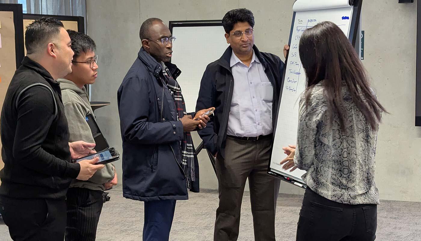 Group work training Training participants stand together in front of a flipchart in the training room.