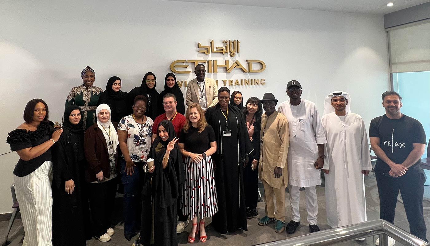 Passenger Experience Management Training in Abu Dhabi Group photo of trainer and participants of a Passenger Experience Management training session in front of the Etihad Aviation Training logo in Abu Dhabi.