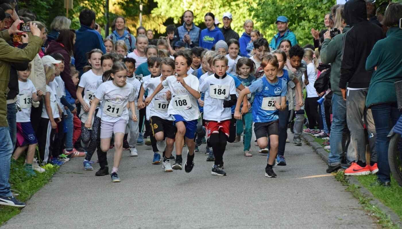 Kinderlauf beim Weihenstephaner Panoramalauf Eine große Gruppe Kinder startet voller Energie in ein Rennen, Gesichter konzentriert und aufgeregt, Zuschauer am Rand feuern sie an, ein Moment voller Bewegung, Gemeinschaft und Freude.