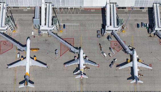 Aerial view of several airplanes parked at passenger gates at an airport terminal.