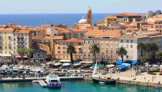 Hafen von Ajaccio – Küstenstadt auf Korsika Blick auf den Hafen von Ajaccio auf Korsika mit Segelbooten, Palmen und pastellfarbenen Häusern der Altstadt. Im Hintergrund liegt das türkisfarbene Mittelmeer und die mediterrane Küste.