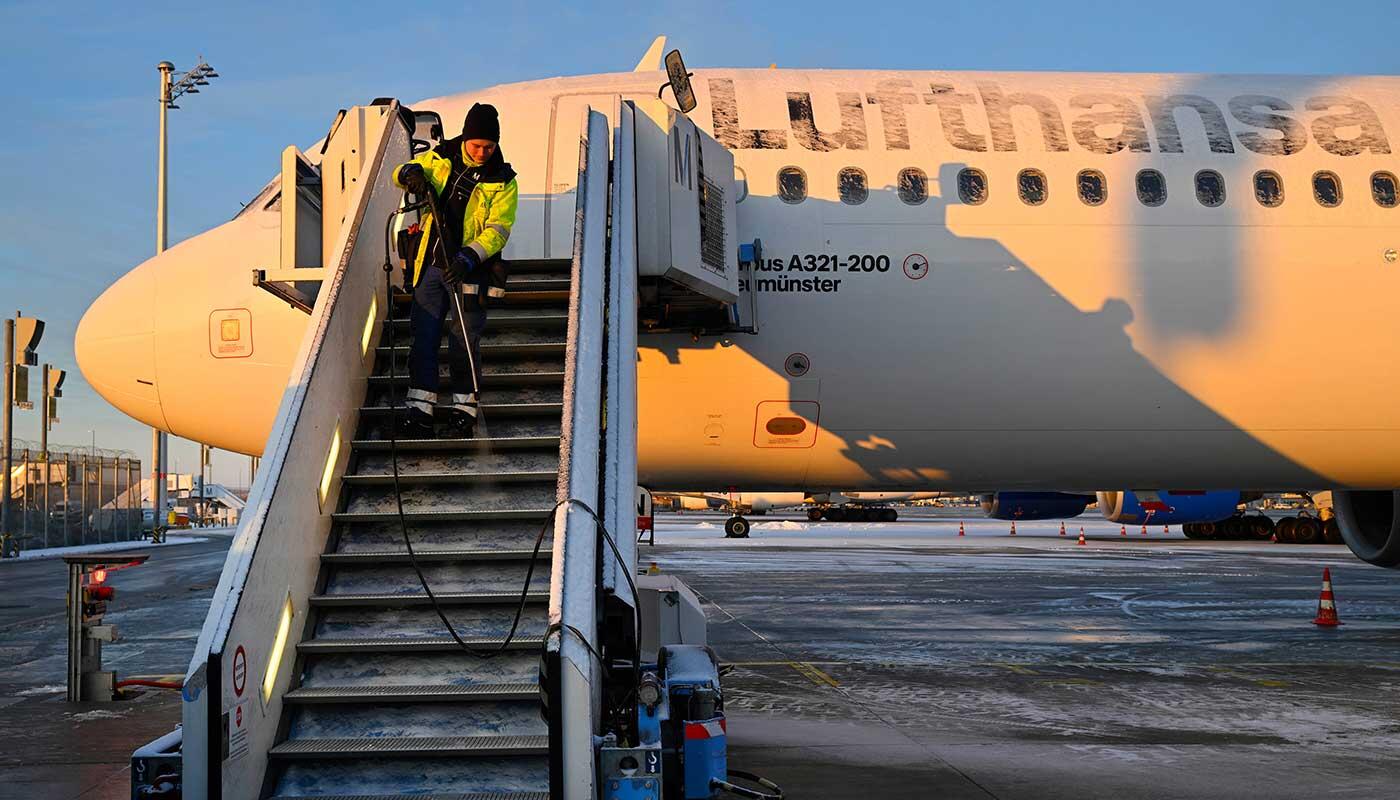 Schnee am Flughafen München Bodenpersonal am Flughafen München enteist bei winterlichen Bedingungen die Flugzeugtreppe eines Lufthansa-Airbus auf dem Vorfeld.