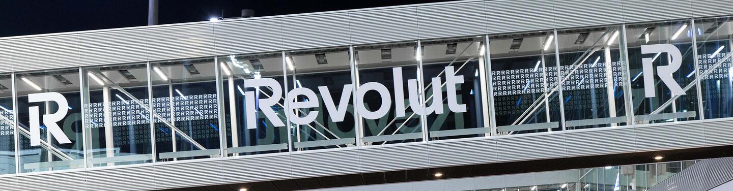 Revolut Branding Übergangsbauwerk Weißer Revolut Schriftzug auf einem gläsernen Übergangsbauwerk - vom Terminalgebäude zu den Fluggastbrücken