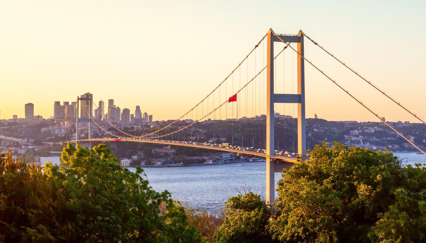 15.-Juli-Märtyrerbrücke in Istanbul, Türkei 15.-Juli-Märtyrerbrücke in Istanbul über den Bosporus. Die Brücke verbindet Europa und Asien und ist von dichtem Stadtgebiet umgeben. Im Hintergrund erkennt man die Skyline Istanbuls mit vielen Hochhäusern und Gebäuden, während im Vordergrund grüne Bäume das Bild einrahmen. Auf der Brücke herrscht reger Autoverkehr.