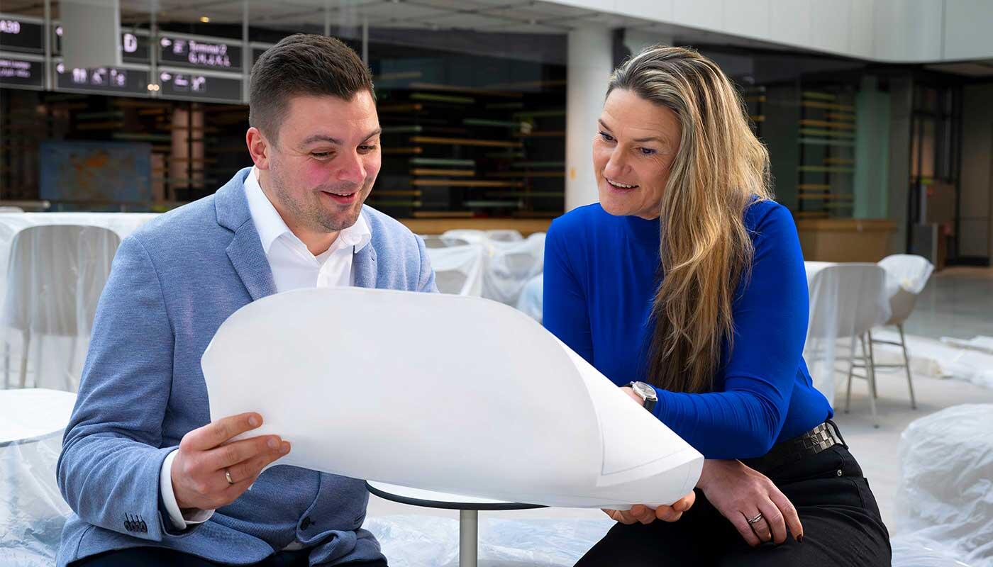Einkaufen und Genießen im Terminal 1-Pier: Wo Fernweh auf Bayern trifft Zwischen Baufolie und Tageslicht wächst die Zukunft: Elke Haeffner wirft mit Markus Ganslmaier, Leiter Produktmanagement Retail & Service am Airport, einen Blick auf die Entwürfe eines der fünf großen Gastronomiebereiche im T1-Pier. Ein besonderer Moment, wenn aus Ideen Räume werden und man plötzlich mittendrin sitzt.