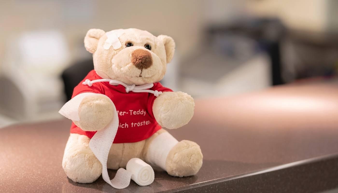Medizinische Beratung und Impfservice für Reisende Ein Teddybär mit Verband sitzt auf einem Behandlungstisch in der Reisemedizin am Flughafen München. Das Bild symbolisiert medizinische Versorgung, Impfungen und Gesundheitsvorsorge für Reisende.