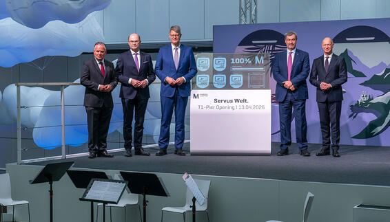 fünf männer stehen neben einem oled display welches 100% anzeigt und den pier eröffnet hat