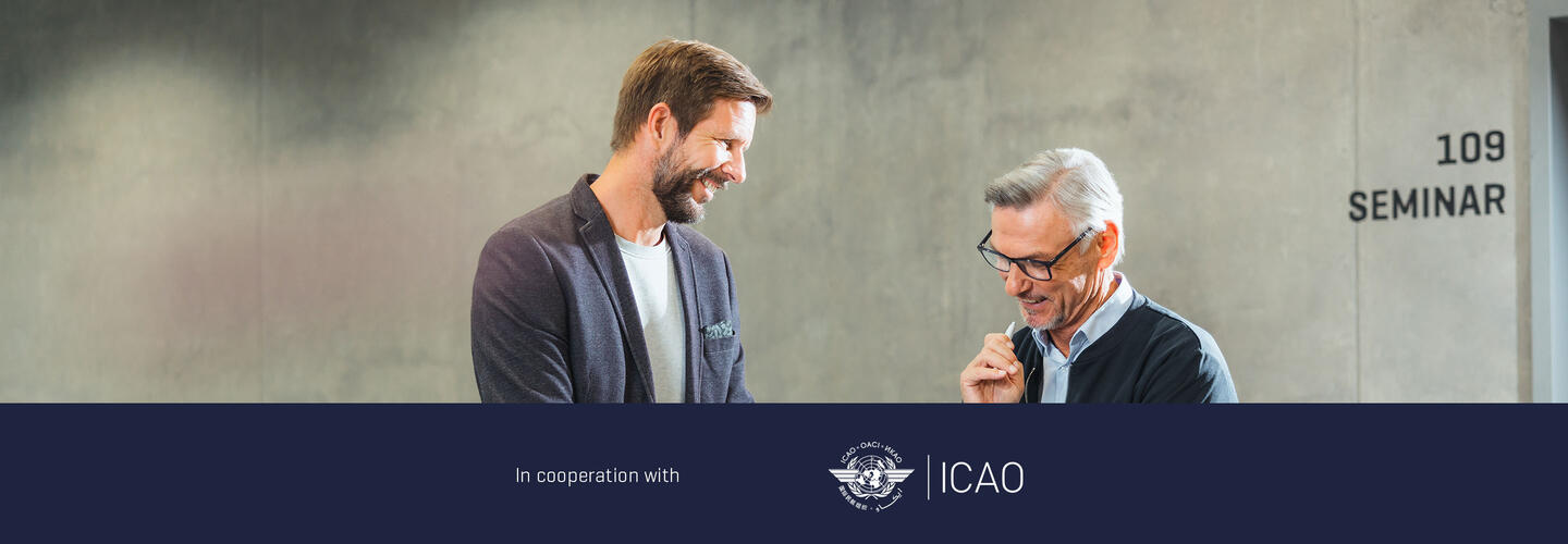 ICAO Training Instructors Course Two people interacting in a seminar room, with signage indicating an ICAO training seminar in the background.