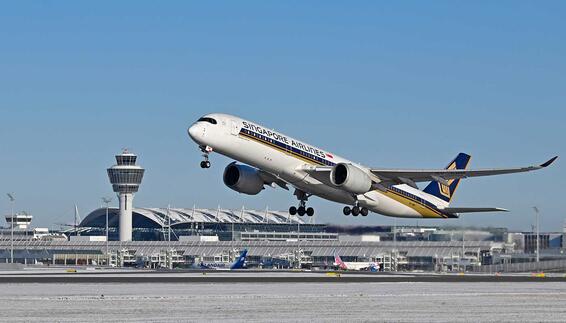 Flugzeuge von Singapore Airlines und Lufthansa auf dem Rollfeld eines internationalen Flughafens mit Terminalgebäude und Kontrollturm im Hintergrund