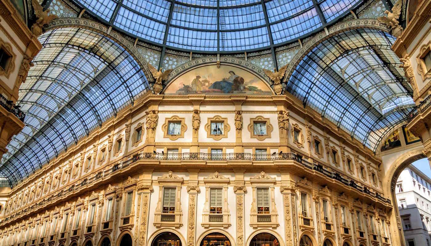 Galleria Vittorio Emanuele II in Mailand, Italien Das Bild zeigt die Galleria Vittorio Emanuele II in Mailand, Italien, eine historische Einkaufspassage mit aufwendiger Architektur und einer großen Glasdach-Kuppel. Zu sehen ist der reich verzierte Innenbereich mit klassischen Fassaden, Balkonen und einem Deckengemälde unter dem Glasdach.